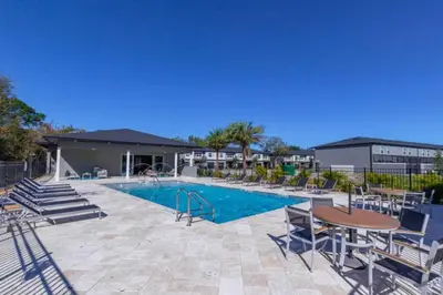 a swimming pool with chairs and a table next to a building at Themed Home Near Disney with Pool in Kissimmee