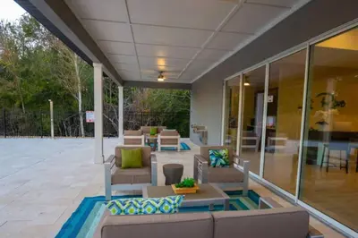 an outdoor patio with couches and tables and windows at Themed Home Near Disney with Pool in Kissimmee