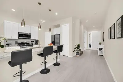 a white kitchen with black chairs and a counter at Enchanted Home Near Disney in Orlando