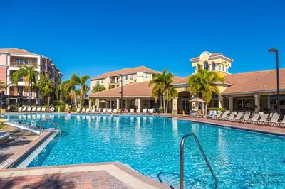 a swimming pool at a resort with chairs and palm trees at Harry Potter-Themed, Lake View, Spacious Condo Near Universal with Extra Amenities in Orlando