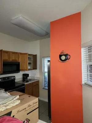 a kitchen with a red wall with a clock on it at Island Abode -near Disney in Kissimmee
