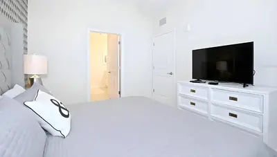 a white bedroom with a white bed and a tv at 3BE&2BA Apartment at Storey Lake Resort 59 in Kissimmee