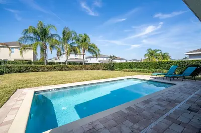 a swimming pool in a yard with two chairs at 510 BS - 5BD Cozy Family Haven with Pool in Orlando