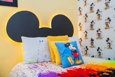a bedroom with a mickey pillow and a wall with mickeys at 510 BS - 5BD Cozy Family Haven with Pool in Orlando