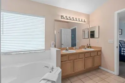 a bathroom with two sinks and a tub and a mirror at Private Pool Close to Disney Lg Hm Slps 8 in Kissimmee