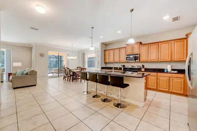 a large kitchen with wooden cabinets and a living room at Spacious 6BR family villa, 10 min to Disney, private pool, resort waterpark in Kissimmee