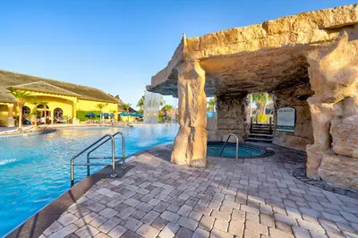 a pool at a resort with a stone wall at Spacious 6BR family villa, 10 min to Disney, private pool, resort waterpark in Kissimmee
