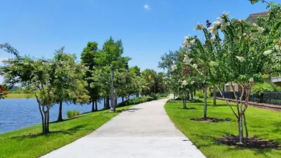 a sidewalk next to a lake with trees at Marvel-Themed, Spacious Condo Near OCCC, Sea World, Disney, and Universal with Extra Amenities in Orlando