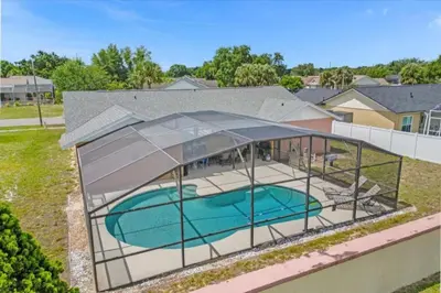 a house with a swimming pool under a glass house at 5Bd 2 Bath with Gameroom & Pool 1 story House in Orlando
