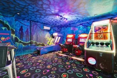 a gaming room with arcade machines and a painting on the wall at Villa Grande in Orlando