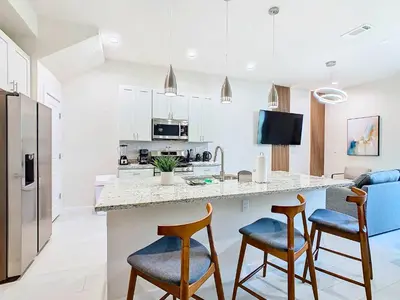 a kitchen with a counter and two bar stools at Fabulous Paradise 3BR Townhouse near Disney and outlets in Orlando