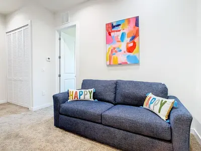 a blue couch in a living room with a painting at Fabulous Paradise 3BR Townhouse near Disney and outlets in Orlando