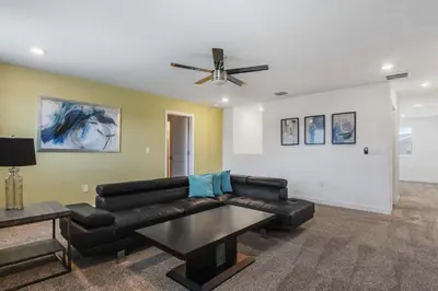 a living room with a black leather couch and a ceiling fan at Lake View Cozy Home w/ Pool & Games Near Disney in Kissimmee