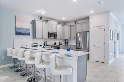a kitchen with white cabinets and a large island with bar stools at Magical 10-Bedroom Disney Getaway Awaits! in Kissimmee