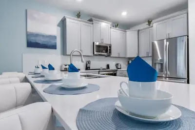 a kitchen with white cabinets and blue bowls on a counter at Magical 10-Bedroom Disney Getaway Awaits! in Kissimmee