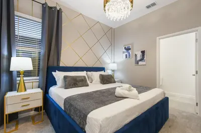 a bedroom with a blue and white bed and a chandelier at Luxury 12BR Villa w/ Pool & Spa Near Disney in Kissimmee