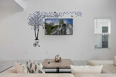 a living room with a couch and a tree on the wall at Luxurious Resort Home Near Disney & Shopping! in Kissimmee