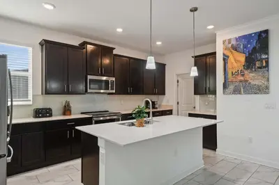a kitchen with wooden cabinets and a white counter top at Luxurious Resort Home Near Disney & Shopping! in Kissimmee