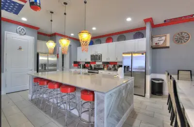 a kitchen with a large island with red bar stools at All Vacation Mansion w Spa-Pool-Cinema Sleep 40 in Kissimmee