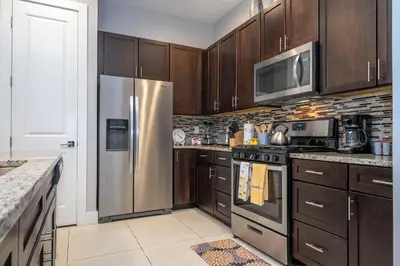 a kitchen with wooden cabinets and a stainless steel refrigerator at Stunning Villa 5 min to Disney in Orlando