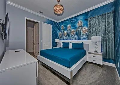 a bedroom with a blue bed and a painting on the wall at Remarkable Mansion Sleep 36 Cinema-Bowling Alley & More in Kissimmee