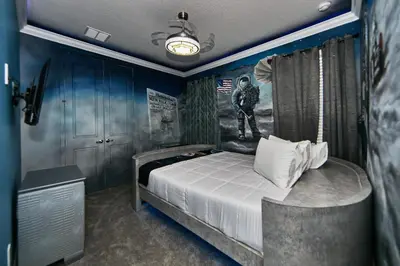 a bedroom with a bed with a painting on the wall at Remarkable Mansion Sleep 36 Cinema-Bowling Alley & More in Kissimmee