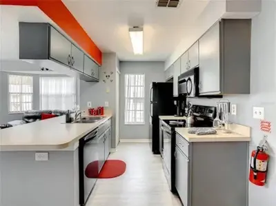 a kitchen with white counters and a red rug at Disney Themed Condo in Kissimmee