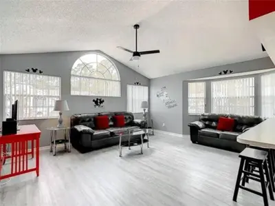 a living room with black couches and red pillows at Disney Themed Condo in Kissimmee