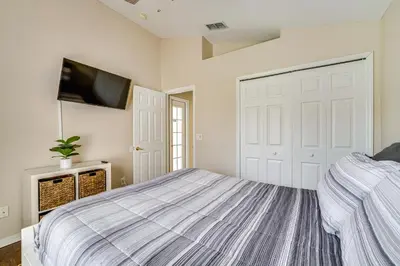 a bedroom with a bed and a flat screen tv at 11 Mi to WDW Kissimmee House with Private Pool! in Kissimmee
