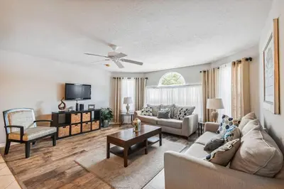 a living room with a couch and a table at SPECTACULAR, NEW Professional Decor, Near Dis, NO Steps, Pool, Patio, LOW Rates! in Kissimmee