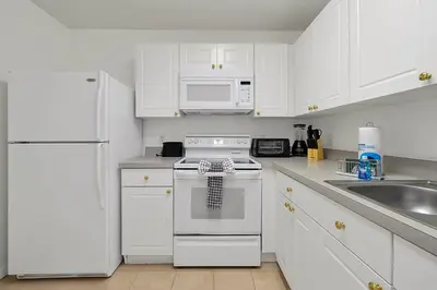a white kitchen with white appliances and white cabinets at Spacious Condo W/ Pool,Gym near Disney & Seaworld in Kissimmee