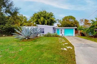 a house with a blue garage in a yard at Boat and Fish! Lake Druid Gem with Dog-Friendly Yard in Orlando