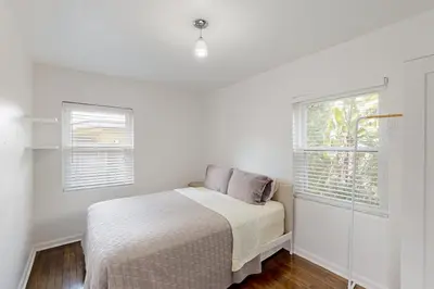 a white bedroom with a bed and two windows at Boat and Fish! Lake Druid Gem with Dog-Friendly Yard in Orlando