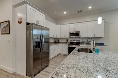a kitchen with white cabinets and a stainless steel refrigerator at The Hub Downtown in Sanford