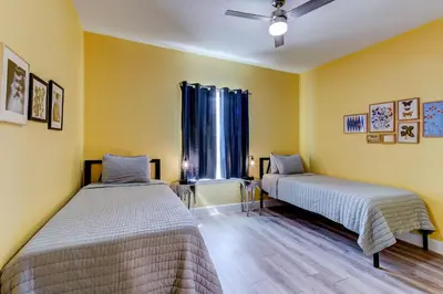 two beds in a room with yellow walls at The Hub Downtown in Sanford