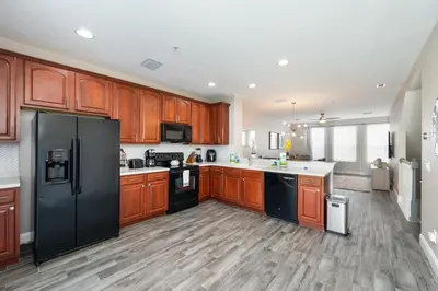 a kitchen with wooden cabinets and a black refrigerator at Beautiful Family Townhome, Near The Parks - 8000-104 in Orlando