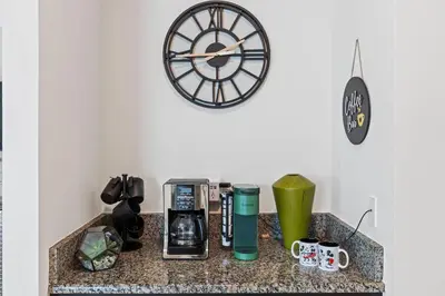 a counter with a coffee maker and a clock on a wall at Perfect Disney Getaway House 6BR5BA • Private Pool at Storey Lake Resort SL4788 in Kissimmee