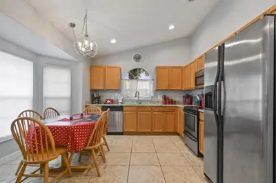a kitchen with a table and a stainless steel refrigerator at Themed 4BR house pool game room 10 min Disney in Orlando