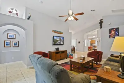 a living room with a couch and a table at Themed 4BR house pool game room 10 min Disney in Orlando