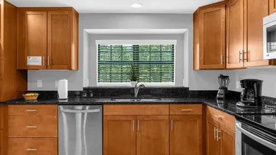 a kitchen with wooden cabinets and a sink and a window at Sunny Stay in FL - 4-Bedroom Townhome by Disney! in Orlando