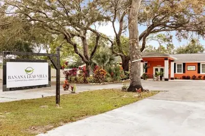 a sign in front of a building with trees at Banana Leaf Villa-Marley Junior Suite with Living Room in Orlando