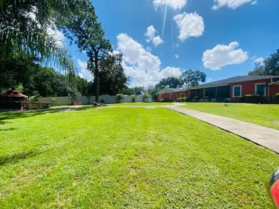 a grassy yard next to a building and a sidewalk at Banana Leaf Villa-Marley Junior Suite with Living Room in Orlando