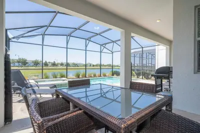 a patio with a glass table and chairs and a swimming pool at Premium 6BR home w/Pool-BBQ just 10min to Disney in Kissimmee