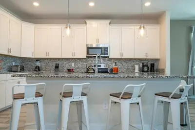 a kitchen with white cabinets and white bar stools at Premium 6BR home w/Pool-BBQ just 10min to Disney in Kissimmee