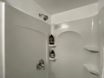 a bathroom with a shower with a bottle of alcohol at Lovely Spacious Guesthouse in Mills 50 District in Orlando