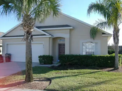 a house with two palm trees in front of it at Orlando Renters in Davenport