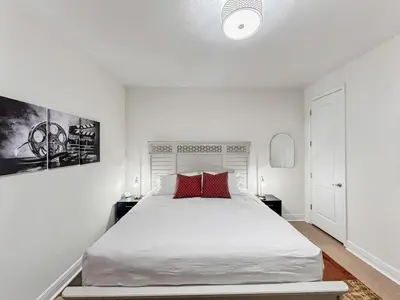 a white bedroom with a large bed with red pillows at Luxury 5BR Villa, Pool Spa, 15min Disney in Orlando