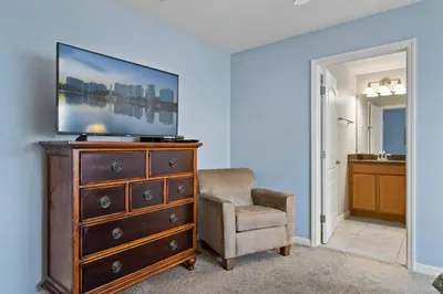 a living room with a dresser with a tv and a chair at 8965 Cozy home Private Pool in Kissimmee