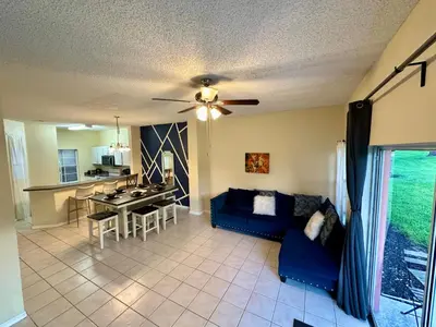 a living room with a blue couch and a ceiling fan at Grand Deluxe 3BR Townhouse near Disney Parks in Kissimmee