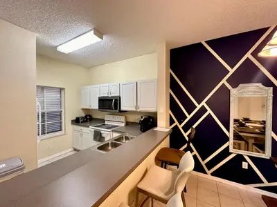 a kitchen with white cabinets and a black wall at Grand Deluxe 3BR Townhouse near Disney Parks in Kissimmee